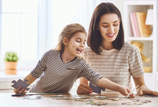 A young girl and her mother work on a puzzle