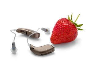 A pair of RITE open dome hearing aids beside a strawberry