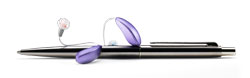 A pair of purple receiver-in-the-ear style hearing aids beside a silver pen