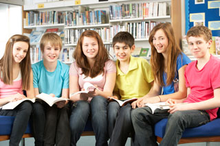 Six high school age children sit in a row with books