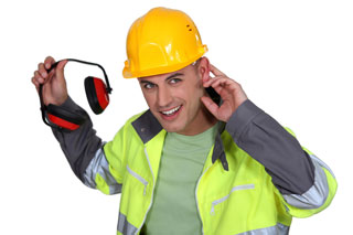 A workman in hard had and fluorescent vest holds hearing protection and a hand behind his ear