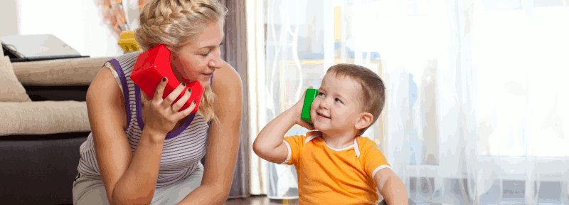 A mother and her son playing with toys and looking at each other