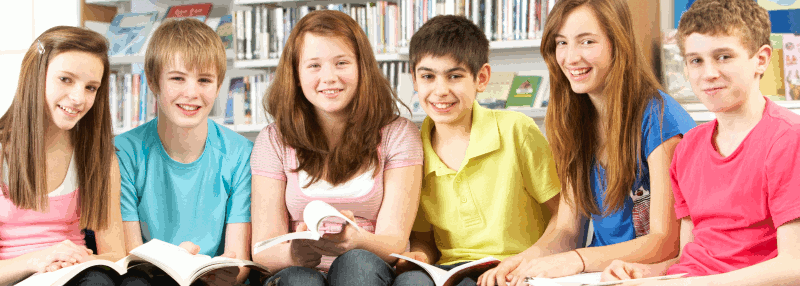 Six high school age children sit in a row with books